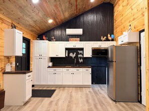 Una cocina con armarios blancos, salpicadero negro y un cartel que dice 'KITCHEN'.