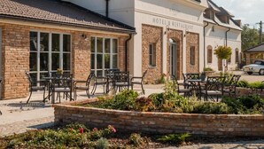 Un hotel con fachada de ladrillo, zona de estar al aire libre y un letrero que indica que es hotel y restaurante.