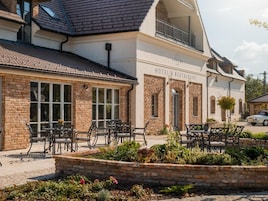 A hotel with a brick facade, outdoor seating area, and a sign indicating it is a hotel and restaurant.