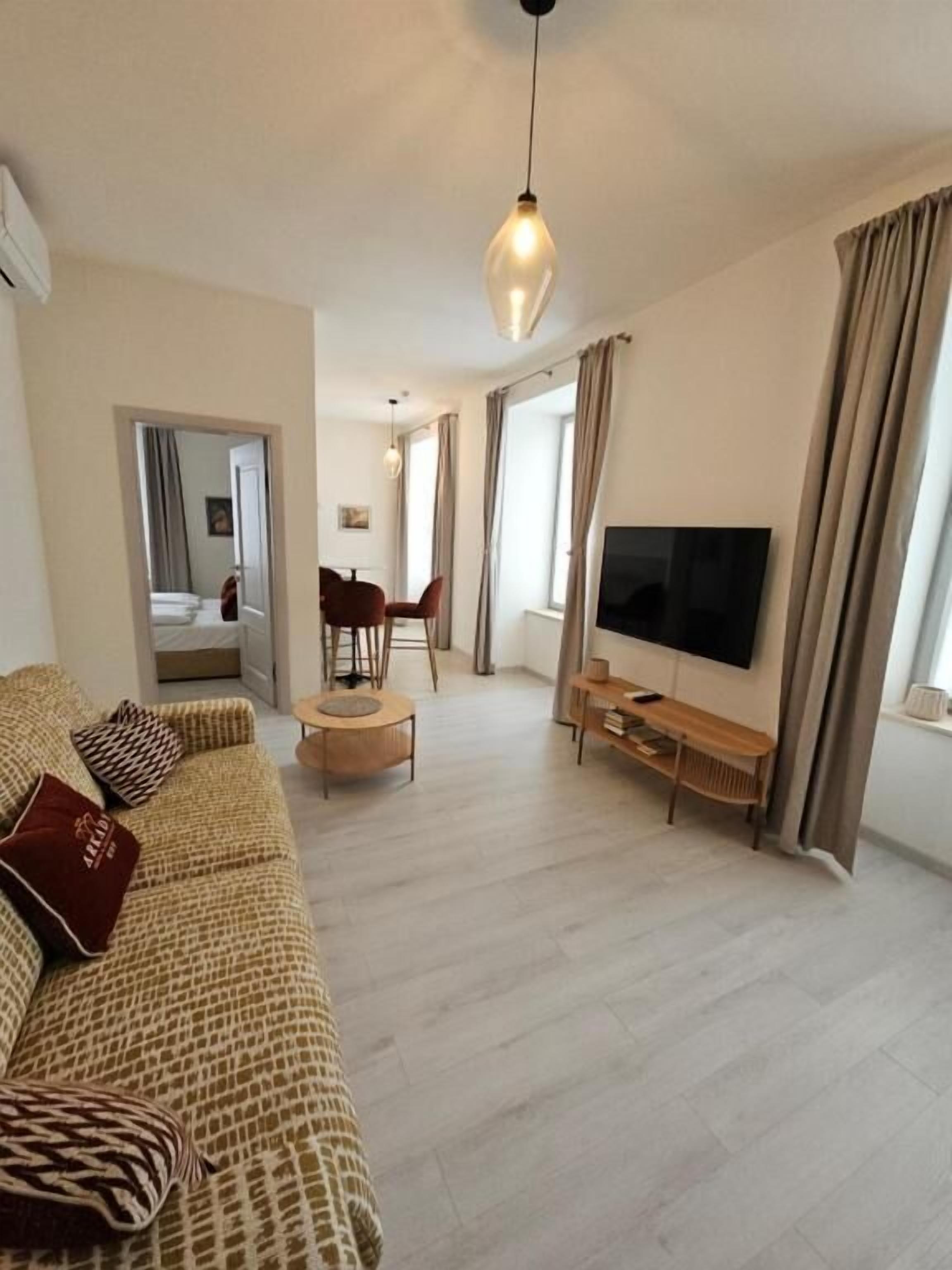 Una sala de estar con sofá, televisor y comedor con sillas y mesa.