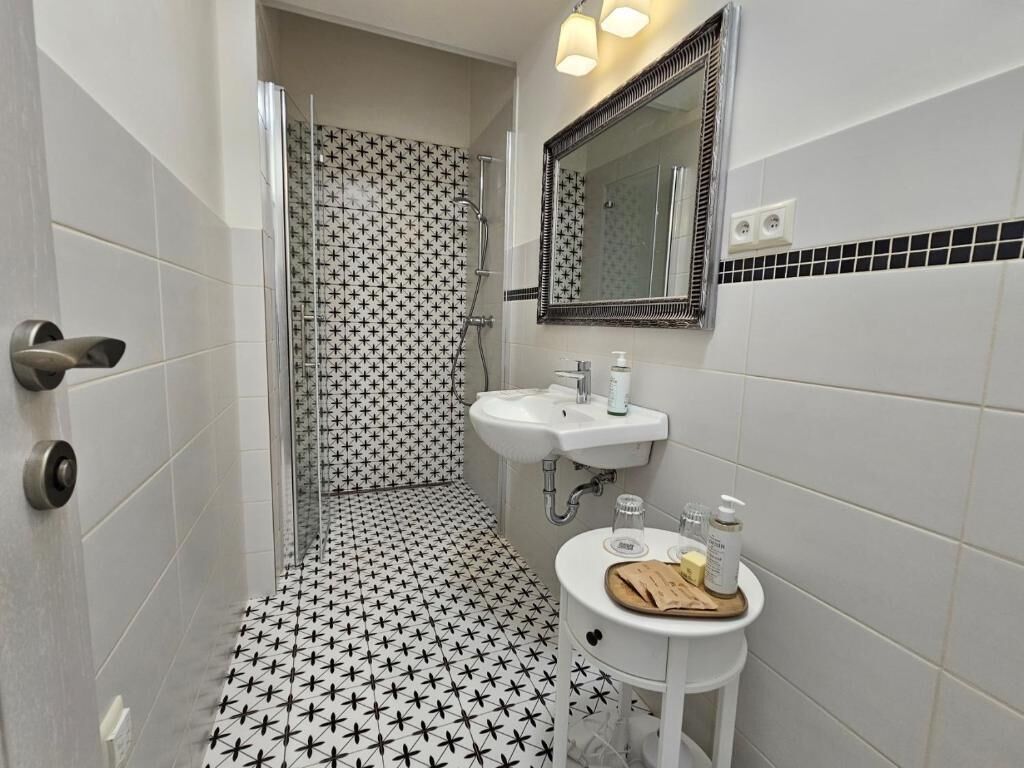A bathroom with a shower, sink, and mirror.
