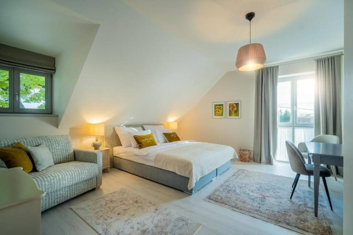 Un dormitorio con cama, mesitas de noche, un sofá, una mesa de comedor y una araña.