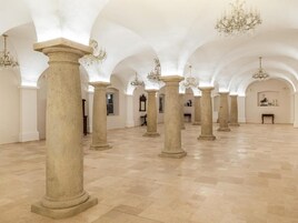 A spacious interior with high ceilings, arched columns, and chandeliers.