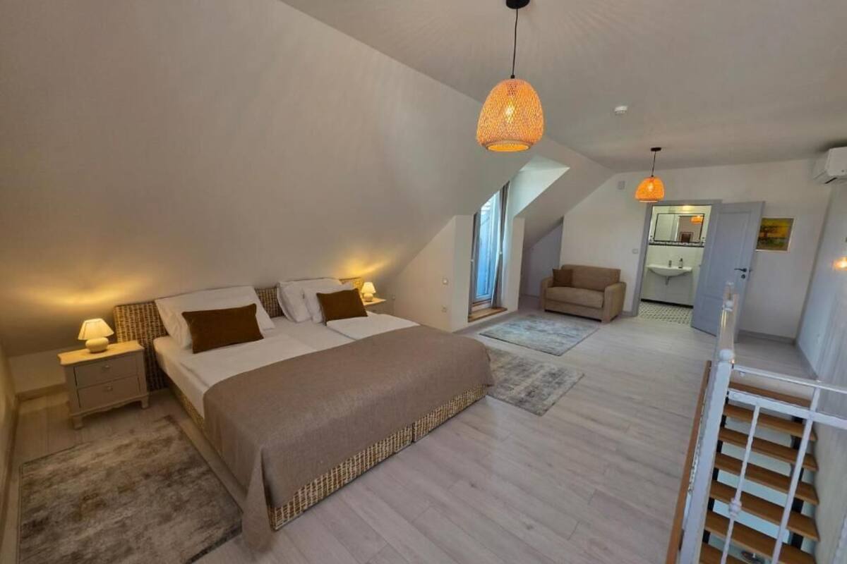 Un dormitorio con una cama grande, una mesita de noche, una lámpara y una lámpara colgante.