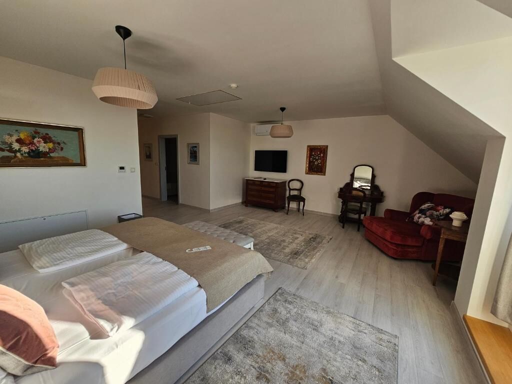 A bedroom with two beds, a desk, a TV, and a red chair.