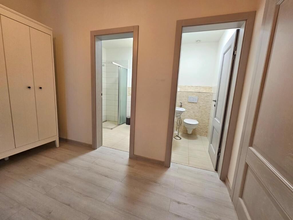 Pasillo que conduce a un baño con inodoro y lavamanos.
