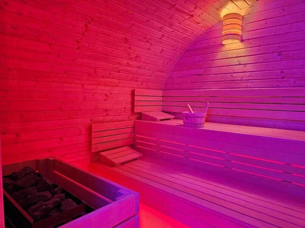 Een sauna met houten banken en een stenen wasbak.