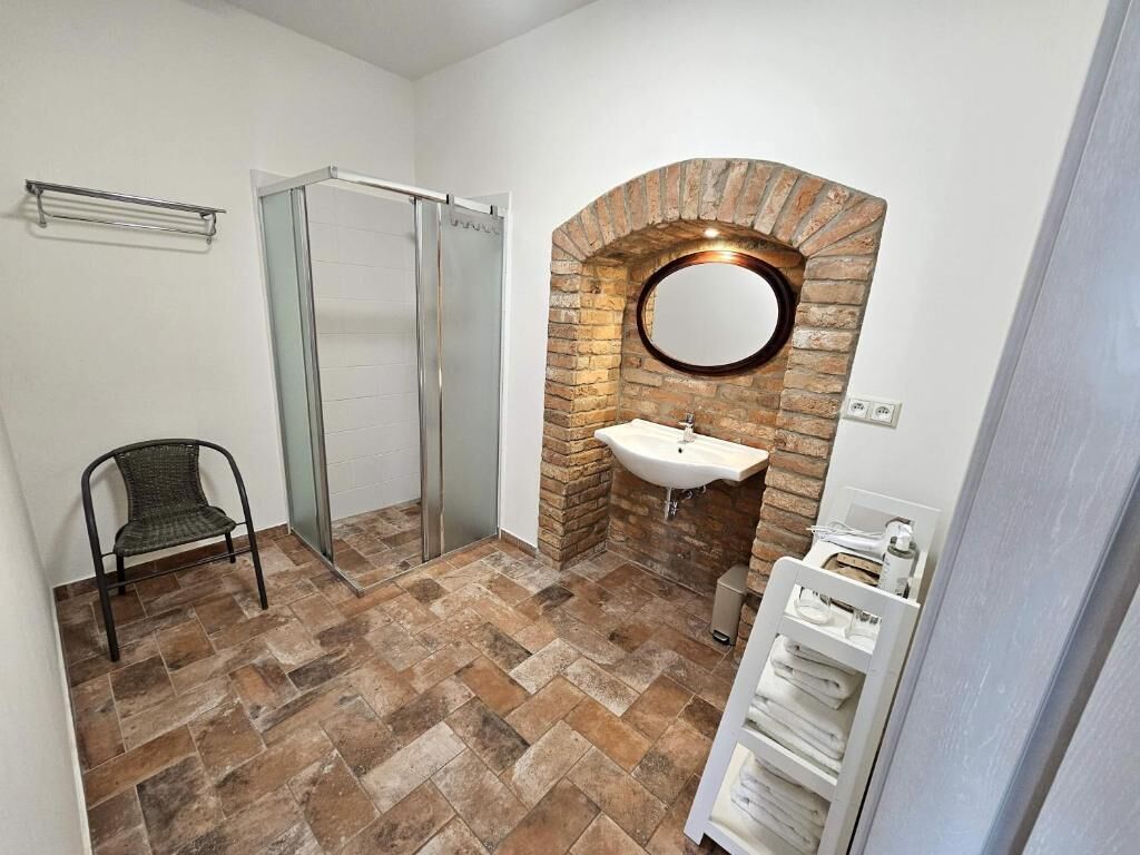 A bathroom with a shower, a sink, a mirror, and a towel rack.