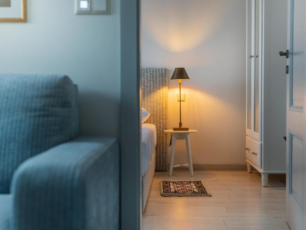 Ett sovrum med en säng, ett nattduksbord med en lampa, en mönstrad matta och en garderob.