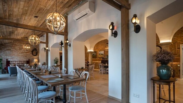 Un comedor amplio con una larga mesa de madera, sillas blancas y lámparas esféricas colgantes.
