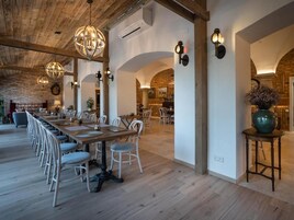 A spacious dining area with a long wooden table, white chairs, and hanging spherical chandeliers.