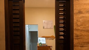 A doorway leading to a room with a wooden bench, a small table with a sign, and a wall-mounted menu board. - Pousada Vila Cactos Jeri (Jijoca de Jericoacoara)