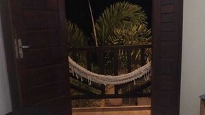 A room with a bed, a hammock, and a view of a palm tree. - Pousada Vila Cactos Jeri (Jijoca de Jericoacoara)