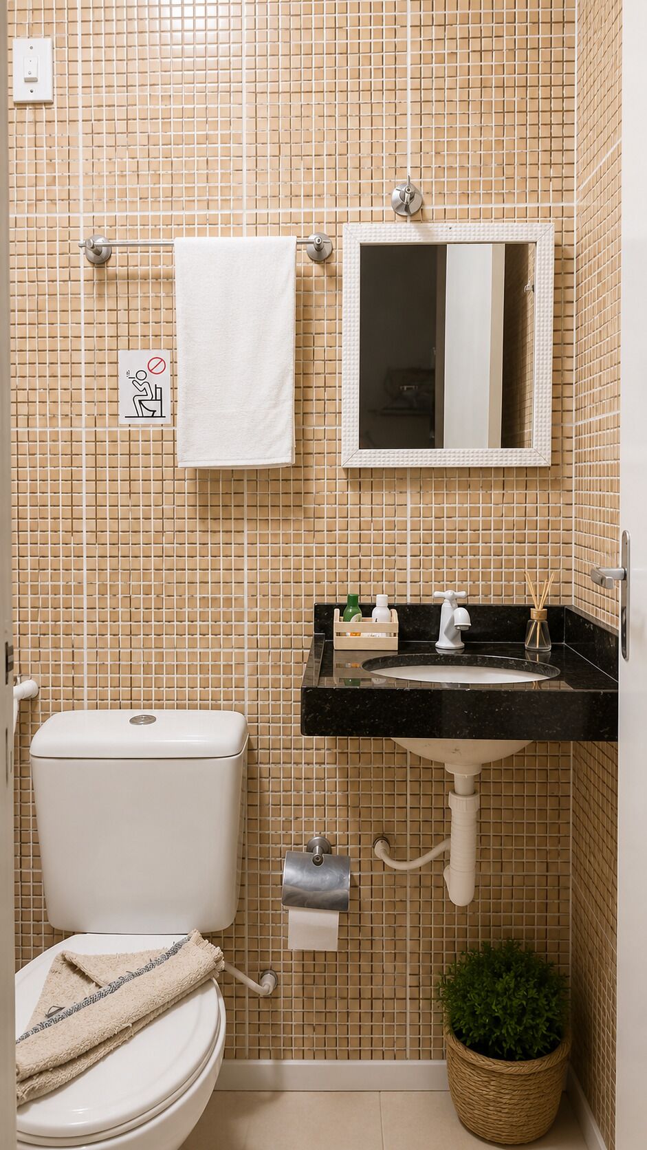 Une salle de bain avec des toilettes, un lavabo, un miroir et une petite plante.