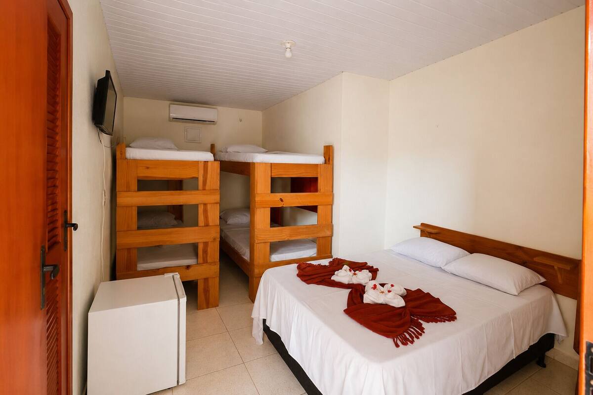 Una habitación con literas, una cama individual, un refrigerador pequeño y un equipo de aire acondicionado.