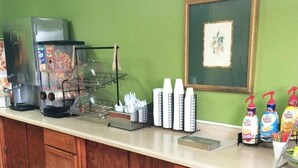 Una cocina equipada con cafetera, dispensadores de condimentos y un cuadro en la pared.