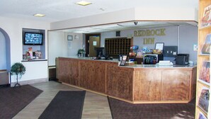 Un mostrador de recepción con detalles de madera, un televisor de pantalla plana y un letrero del Redrock Inn.