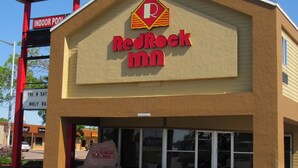 Edificio RedRock Inn con un letrero claro, un cartel de bienvenida y un letrero de estacionamiento.