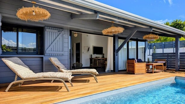 A poolside area with lounge chairs, a wooden deck, and a covered seating area. - La Caze Na Nou - elegant villa with a private pool (Saint Gilles les Bains)