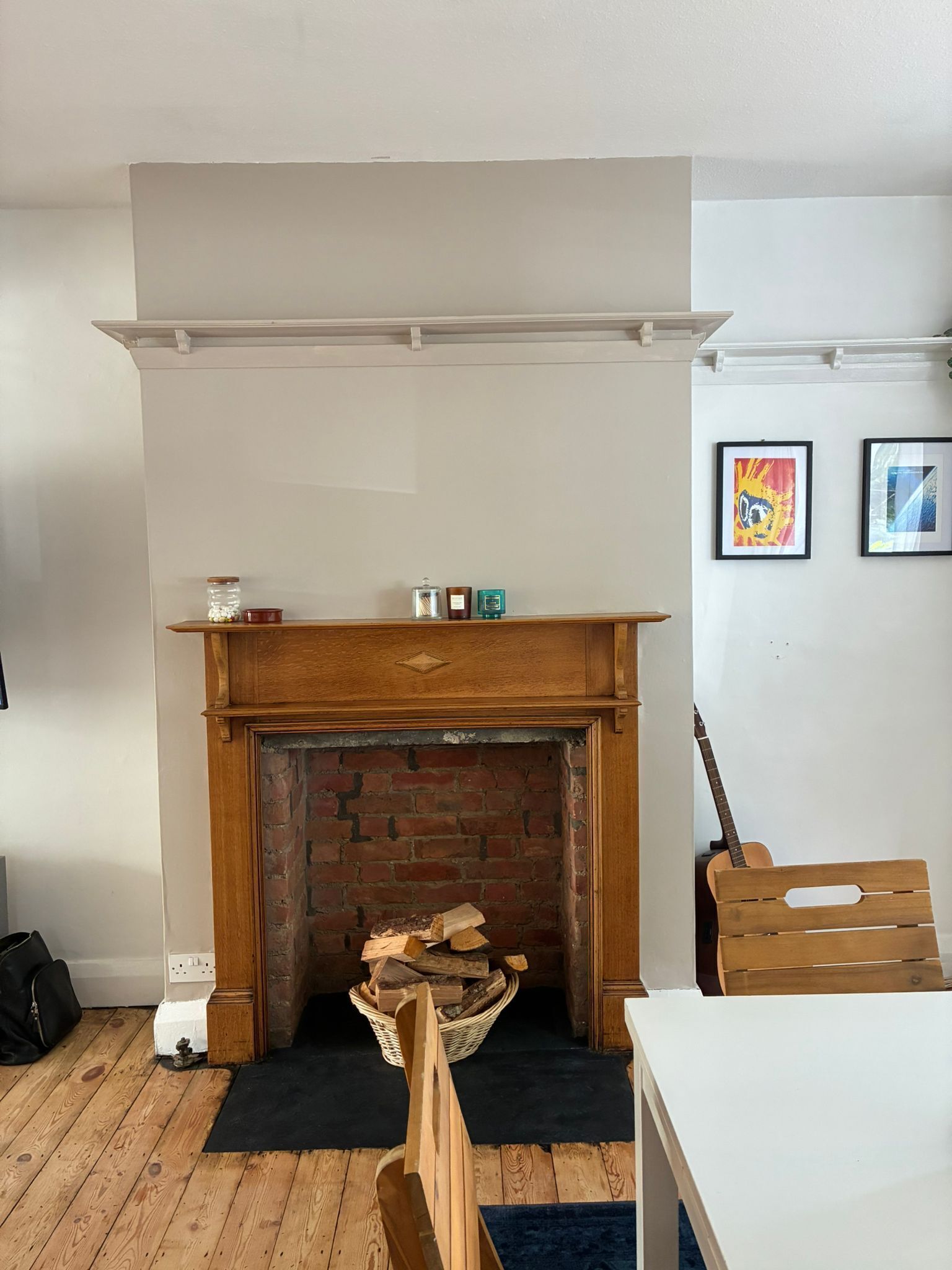 Une pièce avec une cheminée, une guitare et une chaise en bois.