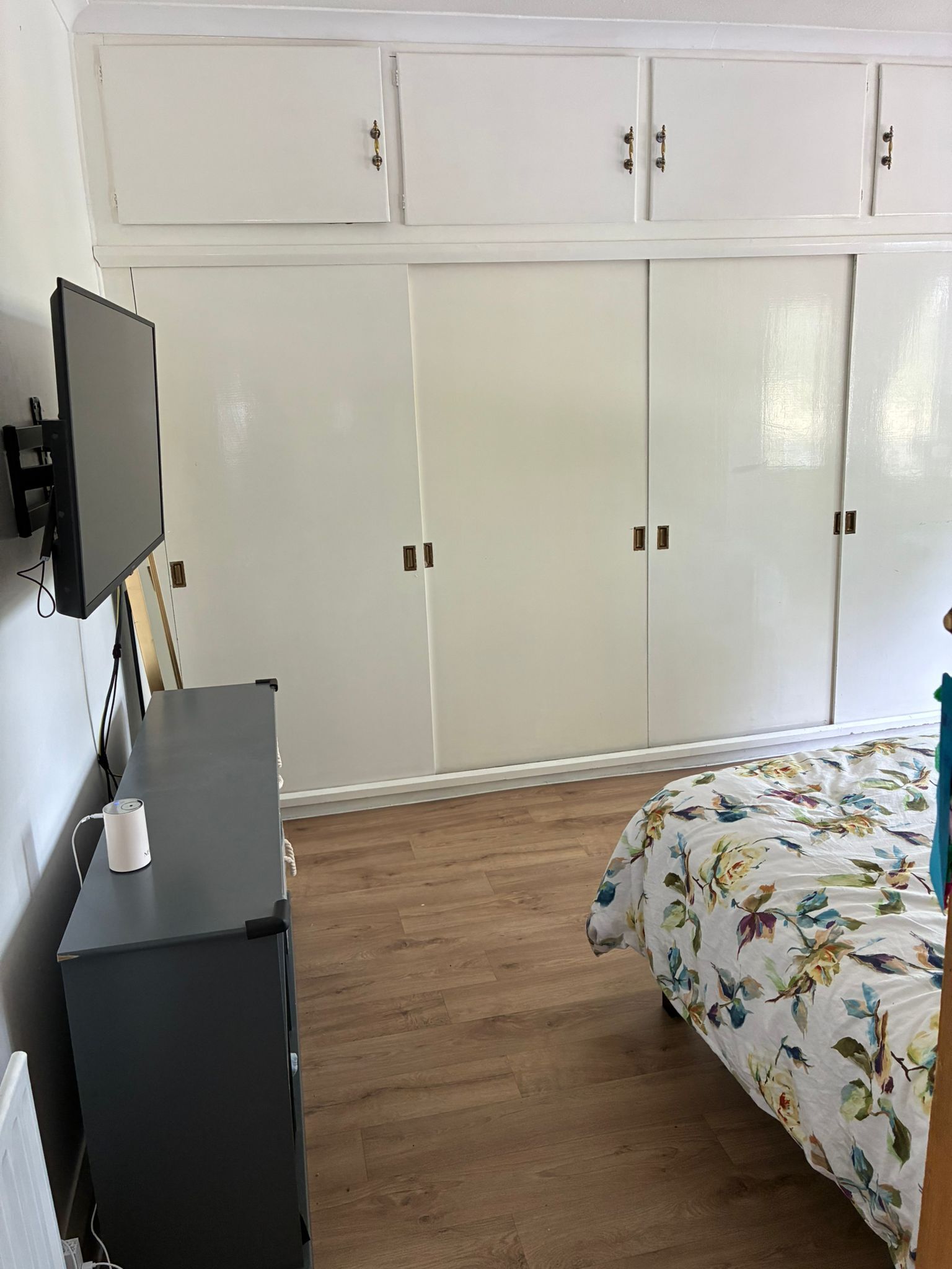 Ein Schlafzimmer mit einem Bett, einem Schreibtisch mit Computer, einem Fernseher und einem Kleiderschrank.