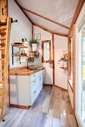 Une cuisine compacte avec des poutres en bois, un évier encastré et une fenêtre.