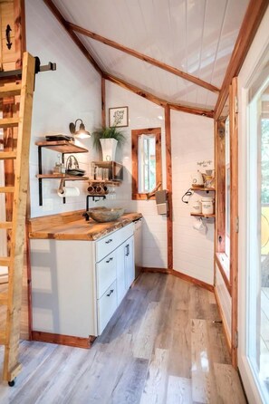 A compact kitchen with wooden beams, a built-in sink, and a window. - Enchanting Forest Treehouse Hideaway with Farm Activities near Bingham Creek in Forestburg, Texas (Forestburg)