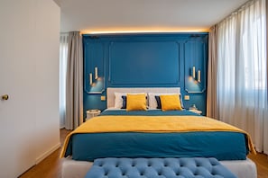 Ein Schlafzimmer mit einem großen Bett, einem gesteppten Kopfteil, Nachttischen und einem Beistelltisch.