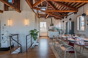 A modern kitchen with a dining area, wooden beams, and a view of the city. - Corte delle Candele Rooftop Views (Venice)
