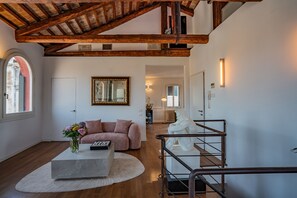 Ein modernes Interieur mit freiliegenden Holzbalken, einer Couch, einem Couchtisch, einer Treppe und einem Spiegel.