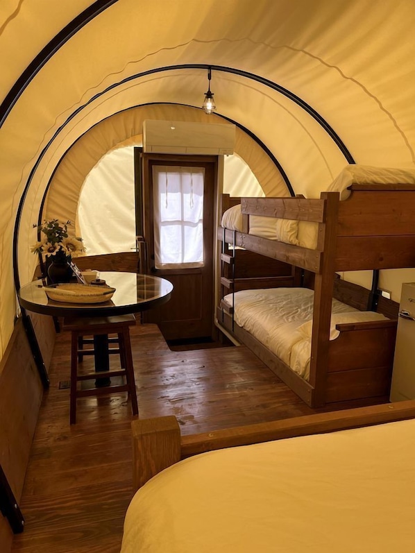 A tent with bunk beds, a table with a vase, and a window.