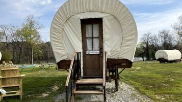 A covered wagon with a wooden door, a sign reading 'Wild Blue,' and a wooden staircase leading up to it.