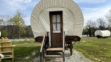 Een overdekte wagen met een houten deur, een bord met de tekst 'Wild Blue' en een houten trap die er naartoe leidt.