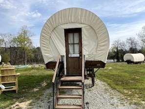 A covered wagon with a wooden door, a sign reading 'Wild Blue,' and a wooden staircase leading up to it.