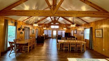 A spacious interior with a high ceiling, wooden walls, and a central dining area.