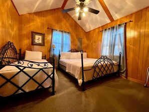 A room with two beds, wooden walls, a ceiling fan, and a framed picture on the wall. - Spacious Lakeview Lodge & Cabin Combo with Fishing Pier Access near Zwolle, Louisiana (Zwolle)