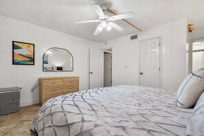 A bedroom with a bed, dresser, mirror, ceiling fan, and a painting on the wall. - 2-bedroom building in phenomenal Indian Shores with AC comfort (Indian Shores)