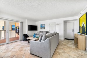 Ein modernes Wohnzimmer mit einem grauen Sofa, einem Flachbildfernseher und einem Gemälde.