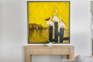 A framed painting of birds and boats on a wall above a wooden console table with a plant. - 2-bedroom building in phenomenal Indian Shores with AC comfort (Indian Shores)