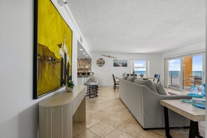 Un espace de vie moderne comprenant un canapé gris, un coin repas et une cuisine.