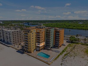 A high-rise building with multiple balconies, a swimming pool, and a view of a river. - 2-bedroom building in phenomenal Indian Shores with AC comfort (Indian Shores)