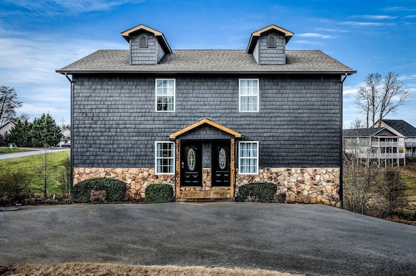 A two-story house with a stone foundation, a dark shingle exterior, and a symmetrical facade with two chimneys. - Comfortable Retreat with Hot-Tub in Sevierville, Tennessee (Sevierville)