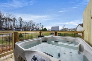 Un bain à remous sur une terrasse, avec des maisons visibles au loin.