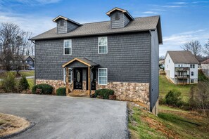 A two-story house with a stone foundation, a front porch, and a driveway. - Comfortable Retreat with Hot-Tub in Sevierville, Tennessee (Sevierville)