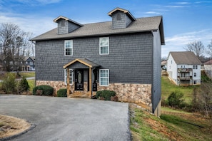 A two-story house with a stone foundation, a front porch, and a driveway. - Comfortable Retreat with Hot-Tub in Sevierville, Tennessee (Sevierville)