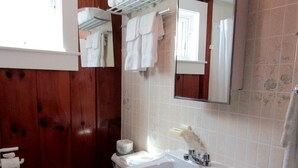 Ein Badezimmer mit einer Holzwand, einem weißen Waschbecken, einer Toilette und einem Spiegel.