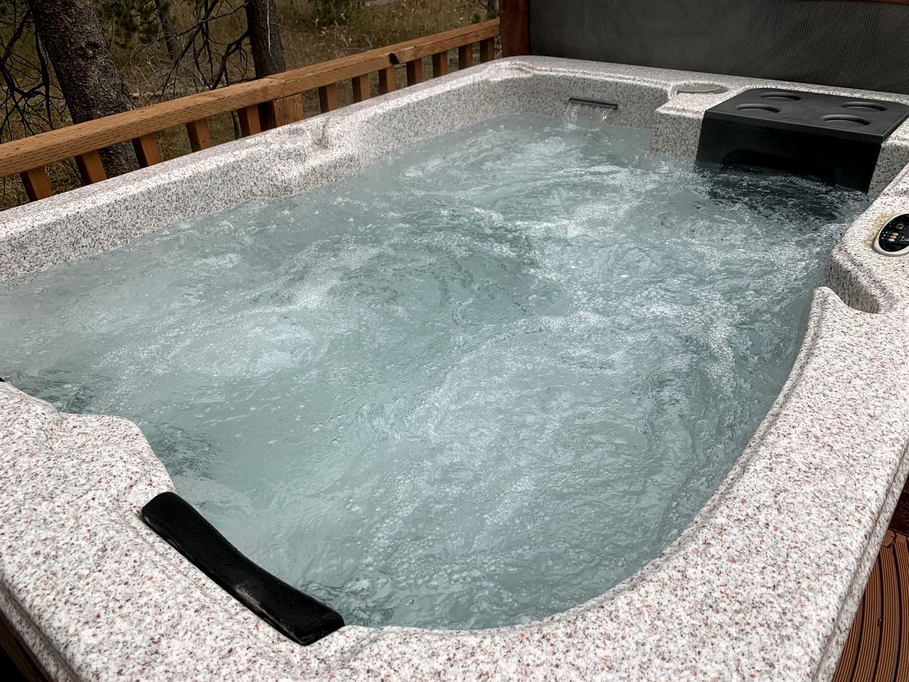 A hot tub with a wooden deck surrounding it.