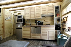 Una cocina compacta con armarios de madera, microondas, refrigerador y pileta.