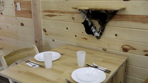 A wooden dining table with plates, cutlery, and a cup, set against a wooden wall with a mounted animal head. - Peaceful Log Cabin Perfect for a Romantic Getaway near Yellowstone, Idaho (Island Park)