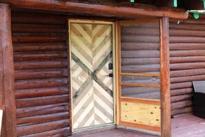 A wooden cabin with a chevron-patterned door, a small porch area, and a visible window. - Peaceful Log Cabin Perfect for a Romantic Getaway near Yellowstone, Idaho (Island Park)